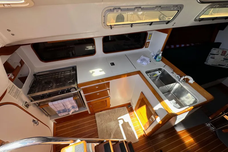 Slide: The Image of Interior of 1996 J Boats J/120 sailboat featuring a compact kitchen with stove and sink. - 36