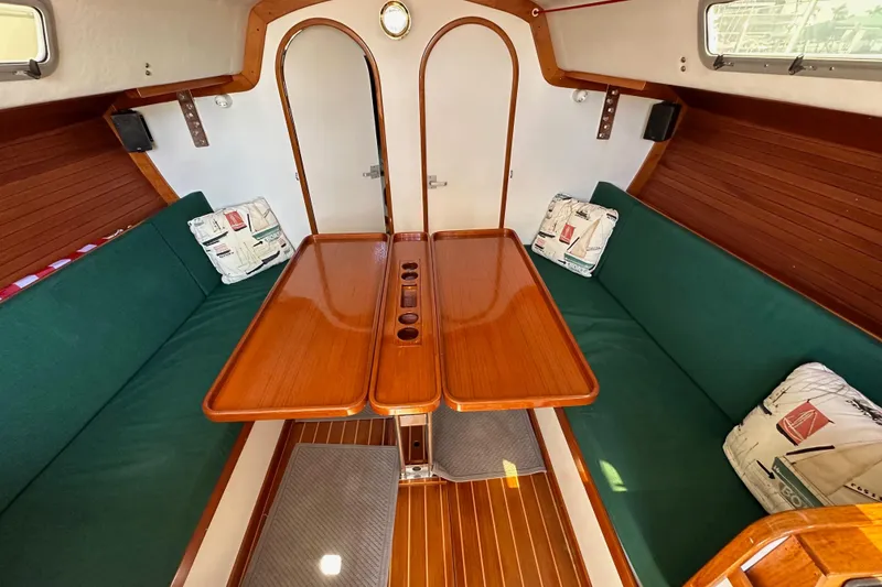 Slide: The Image of Interior of 1996 J Boats J/120 sailboat with wooden table and green seating. - 60