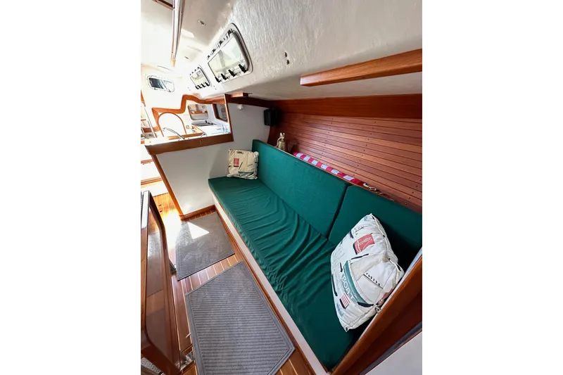 Slide: The Image of 1996 J Boats J/120 interior with green cushioned seating and nautical-themed pillows. - 82