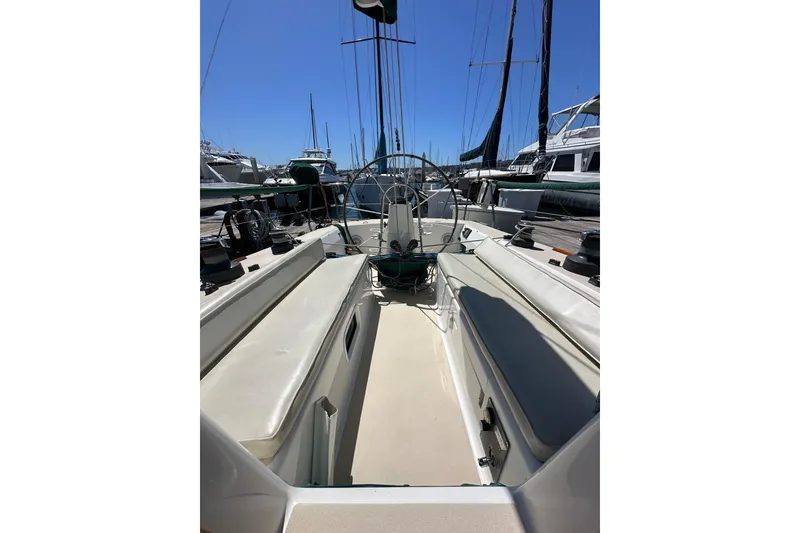 Slide: The Image of 1996 J Boats J/120 sailboat cockpit with seating and steering wheel, docked at marina. - 86