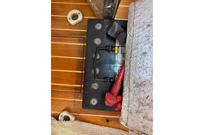 Slide: The Image of Battery compartment of a 1996 J Boats J/120 sailboat with red cables and wooden flooring. - 89