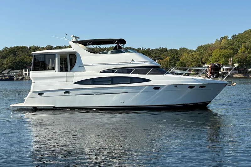 Slide: The Image of 2002 Carver 506 Motor Yacht cruising on a calm lake under clear skies. - 11