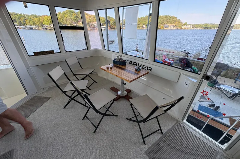 Slide: The Image of 2002 Carver 506 Motor Yacht interior with chairs and table, overlooking serene lake view. - 13