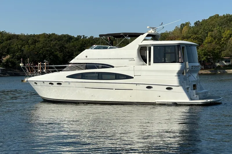 Slide: The Image of 2002 Carver 506 Motor Yacht on a serene lake, surrounded by lush greenery. - 2