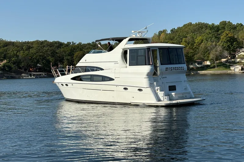 Slide: The Image of 2002 Carver 506 Motor Yacht cruising on a serene lake with lush green shoreline. - 3