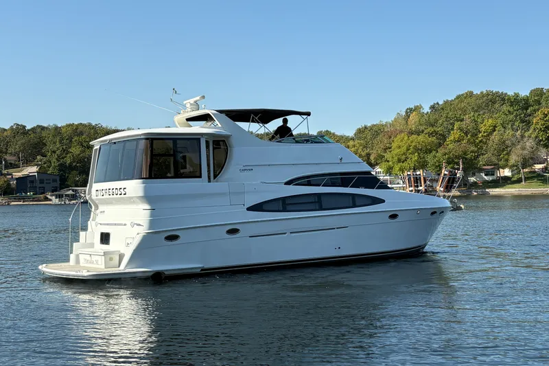 Slide: The Image of 2002 Carver 506 Motor Yacht on a serene lake with lush green shoreline. - 6