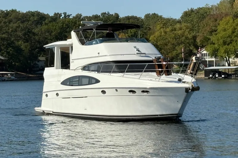 Slide: The Image of 2002 Carver 506 Motor Yacht cruising on a serene lake with lush green surroundings. - 7