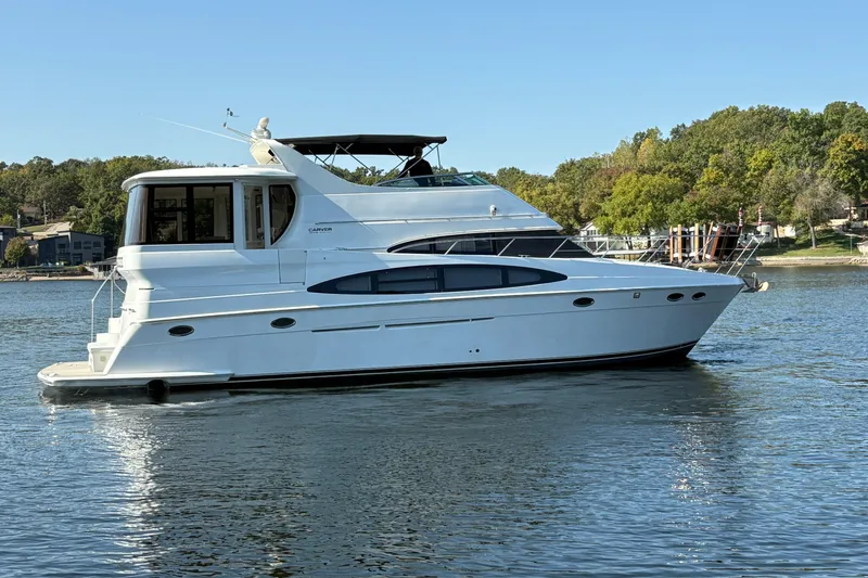 Slide: The Image of 2002 Carver 506 Motor Yacht on a serene lake with lush green shoreline. - 9