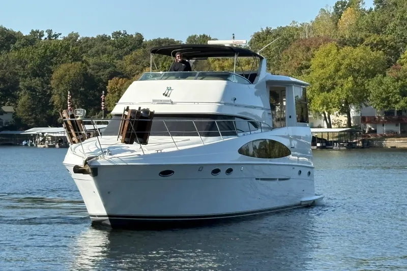 Slide: The Image of 2002 Carver 506 Motor Yacht cruising on a serene lake with lush green surroundings. - 4