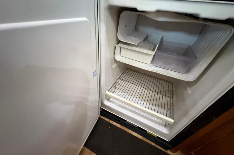 Slide: The Image of Open freezer compartment in 2002 Carver 506 Motor Yacht, showing empty shelves and ice tray. - 42