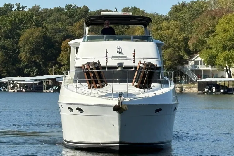 Slide: The Image of 2002 Carver 506 Motor Yacht cruising on a serene lake with lush green surroundings. - 5