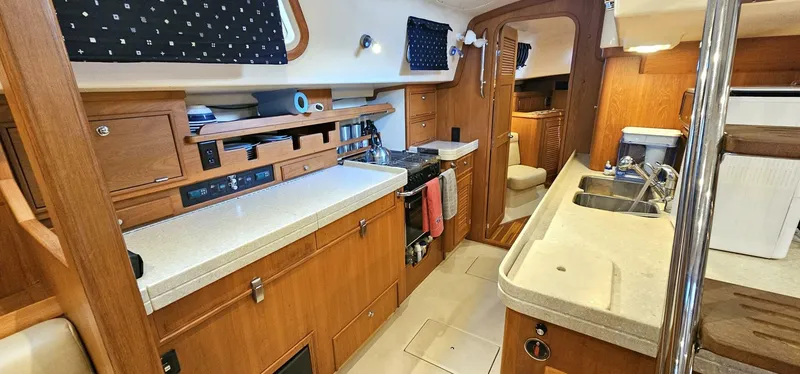 Slide: The Image of Interior of 2009 Island Packet 465 yacht, featuring a well-equipped kitchen with wooden cabinetry. - 6