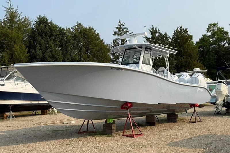 Slide: The Image of 2025 Yellowfin 36 Offshore boat on display, elevated on stands, surrounded by trees. - 31