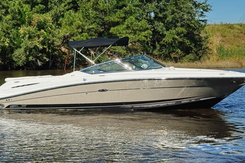 Slide: The Image of 2006 Sea Ray 270 SLX boat on calm water, surrounded by lush greenery. - 1