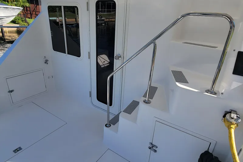 Slide: The Image of Zeta 32 Power Cat 2001 boat interior with stairs and door, featuring sleek design and storage compartments. - 26
