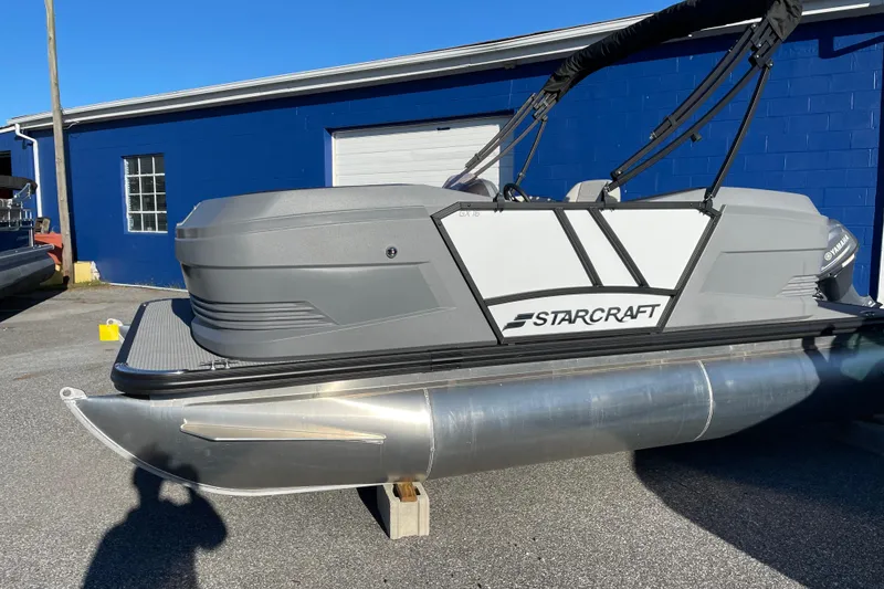 Slide: The Image of 2026 Starcraft GX 16 R pontoon boat displayed outdoors near a blue building. - 11