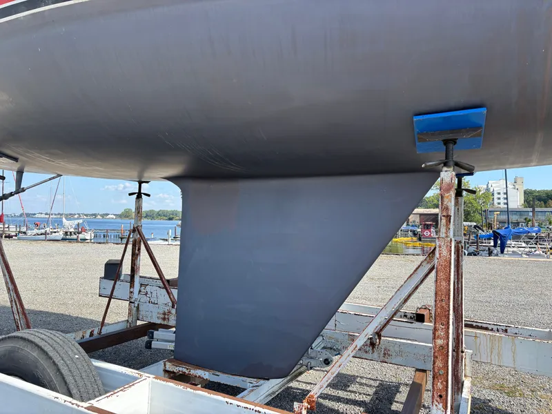 Slide: The Image of 1987 Goman Express 35 sailboat keel on trailer at marina, clear sky background. - 11