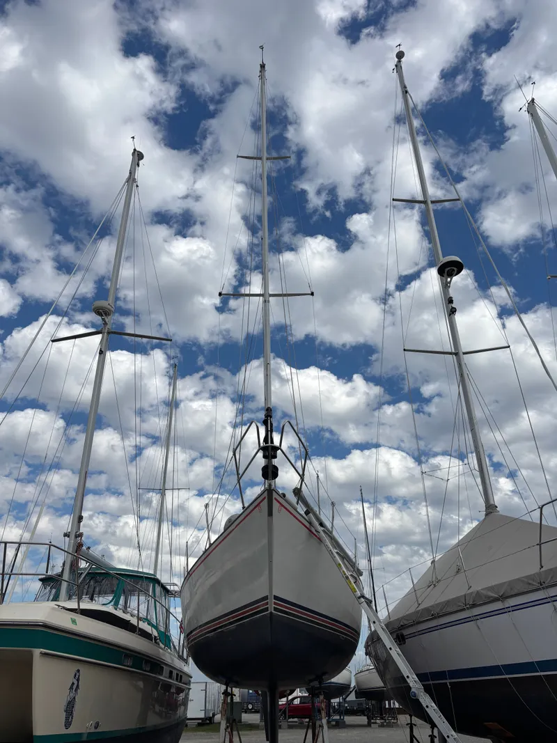 Slide: The Image of Sailboats, including a 1987 Goman Express 35, docked under a cloudy sky. - 13