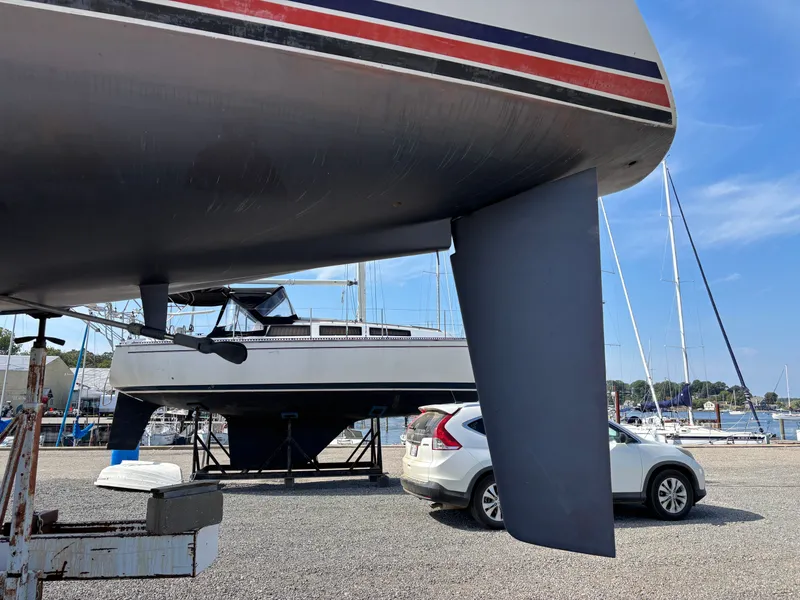 Slide: The Image of 1987 Goman Express 35 sailboat on land, with a car and marina in the background. - 9