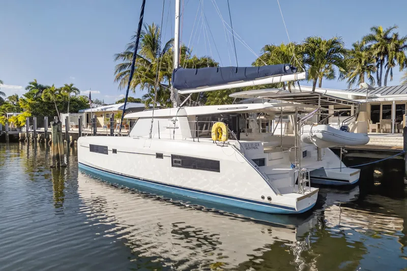 Slide: The Image of 2019 Leopard 45 catamaran docked by palm trees and waterfront homes. - 28