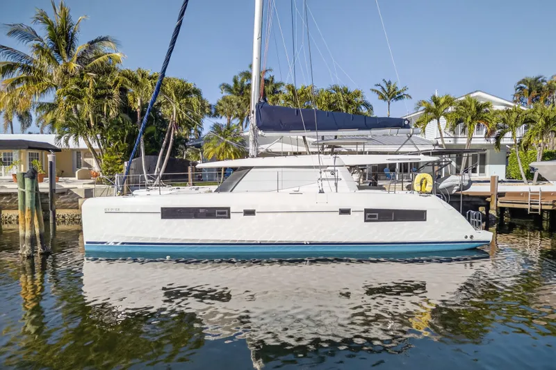 Slide: The Image of 2019 Leopard 45 catamaran docked by palm trees, reflecting on calm water. - 29