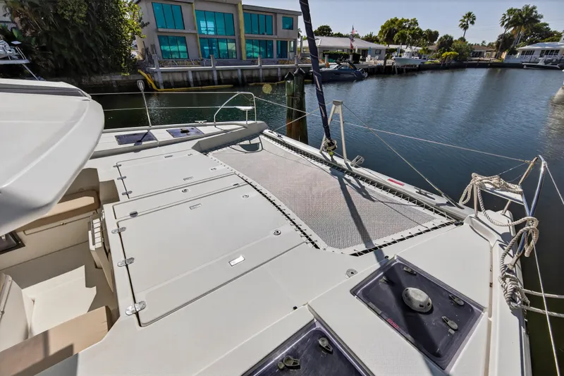 Slide: The Image of 2019 Leopard 45 catamaran docked, featuring spacious deck and netting area. - 52