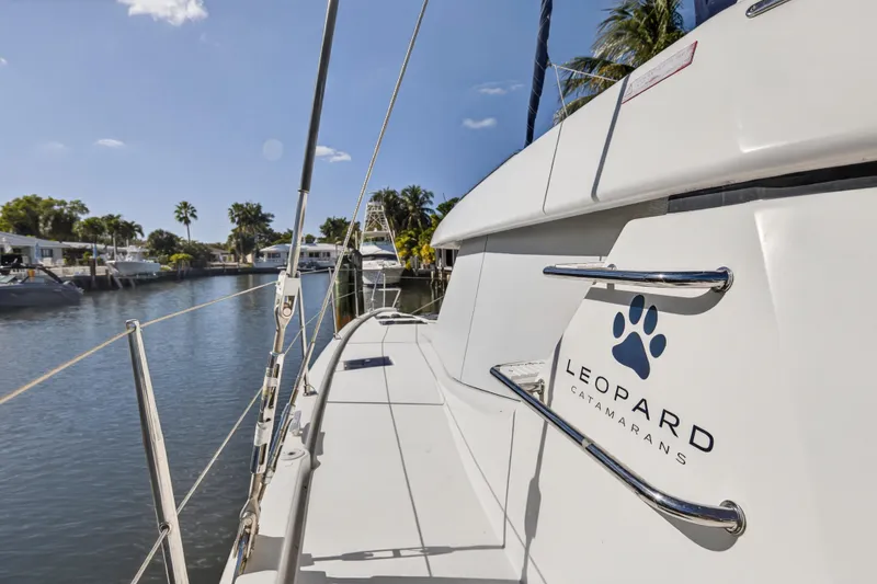 Slide: The Image of 2019 Leopard 45 catamaran docked in a sunny marina, showcasing sleek design and branding. - 66