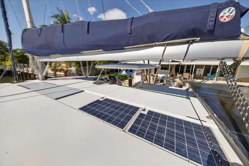 Slide: The Image of 2019 Leopard 45 catamaran with solar panels and covered sail, docked near a waterfront home. - 69