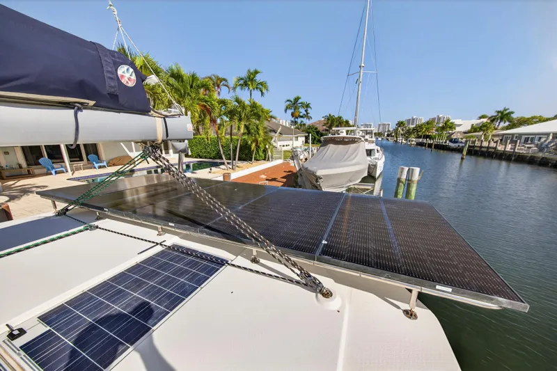 Slide: The Image of 2019 Leopard 45 catamaran with solar panels docked by a canal, surrounded by palm trees. - 70