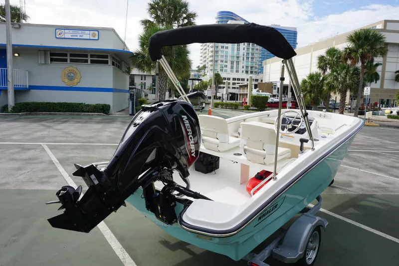 Slide: The Image of 2026 Boston Whaler 130 Super Sport boat with Mercury engine, parked near marine unit building. - 3