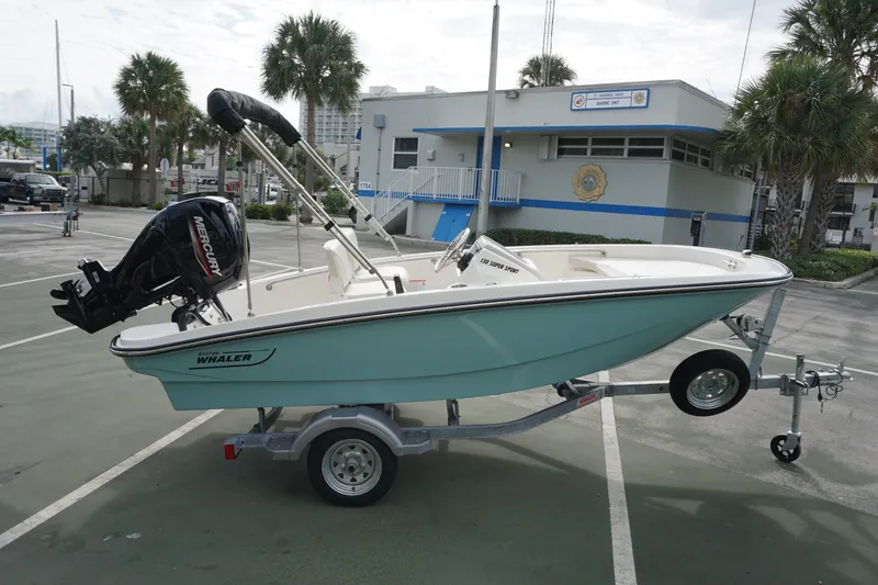 Slide: The Image of 2026 Boston Whaler 130 Super Sport boat on trailer, parked near marine unit building. - 4