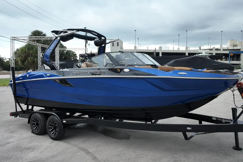 The Image of 2025 Centurion Fe23 boat in vibrant blue on a trailer, parked outdoors. - 1