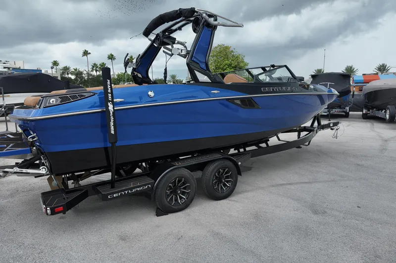 Slide: The Image of 2025 Centurion Fe23 boat in blue on a trailer, parked outdoors under cloudy skies. - 6