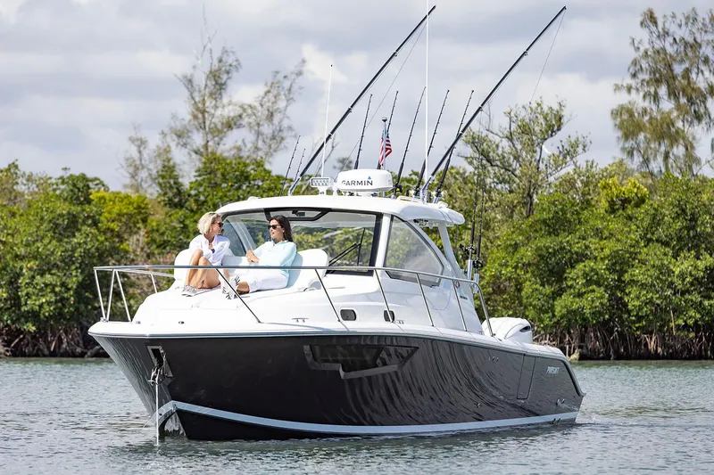 Slide: The Image of Manufacturer Provided Image: 2025 Pursuit OS 325 Offshore boat cruising on a calm lake with two passengers. - 2