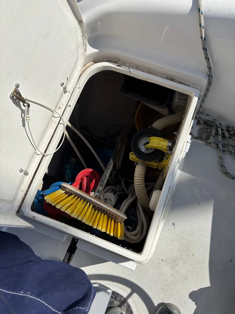 Slide: The Image of Open storage compartment on 2000 Catalina 380 sailboat with ropes and cleaning supplies. - 38