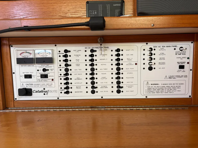 Slide: The Image of Electrical control panel of a 2000 Catalina 380 yacht, featuring various switches and gauges. - 49