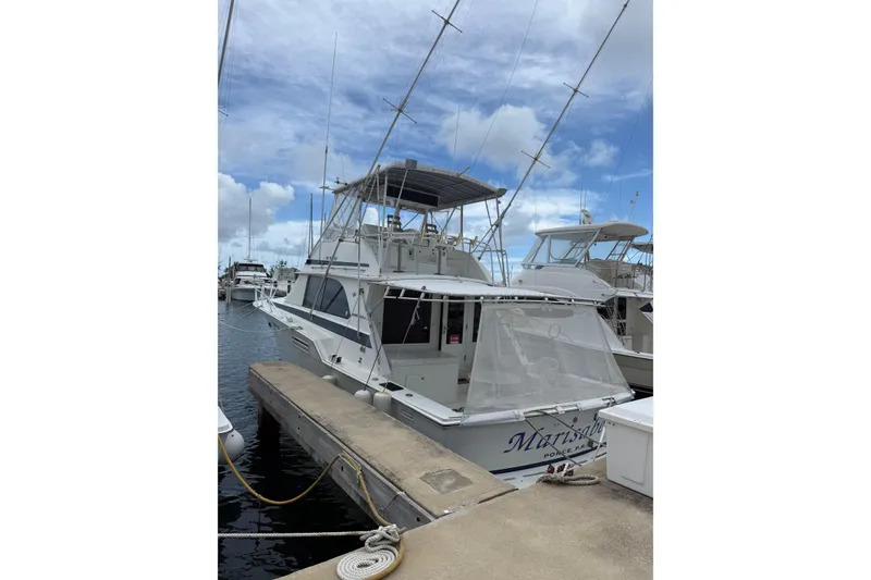 The Image of 1984 Bertram 46 Convertible yacht docked at marina under cloudy sky. - 1