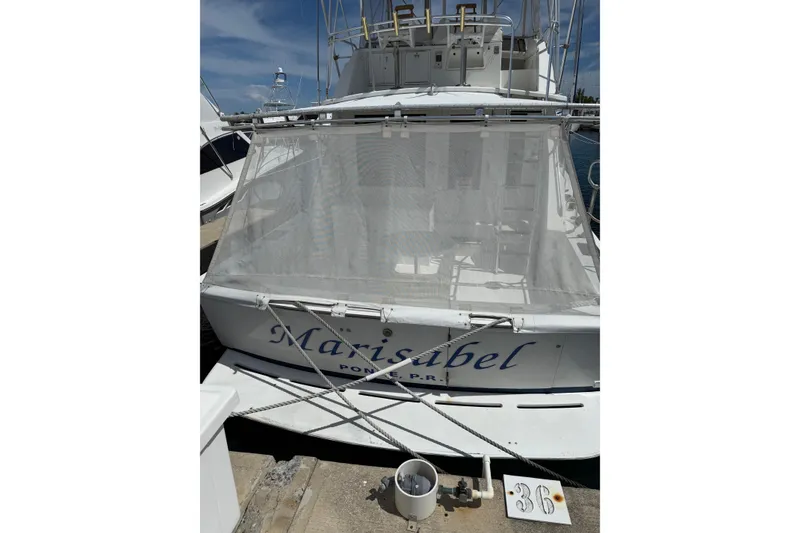 Slide: The Image of 1984 Bertram 46 Convertible yacht docked, rear view with name "Marisabel" visible. - 3