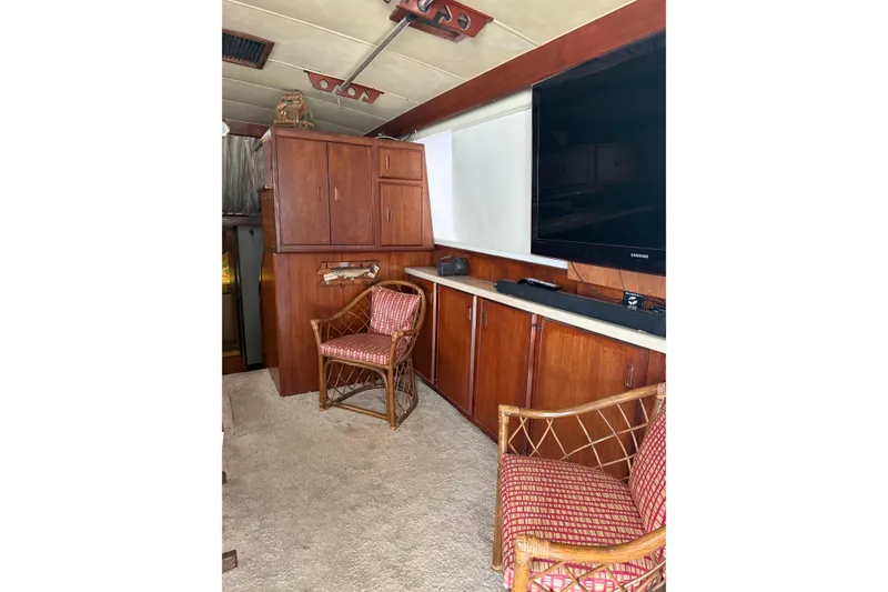 Slide: The Image of 1984 Bertram 46 Convertible interior with wooden cabinets, chairs, and a large TV. - 9