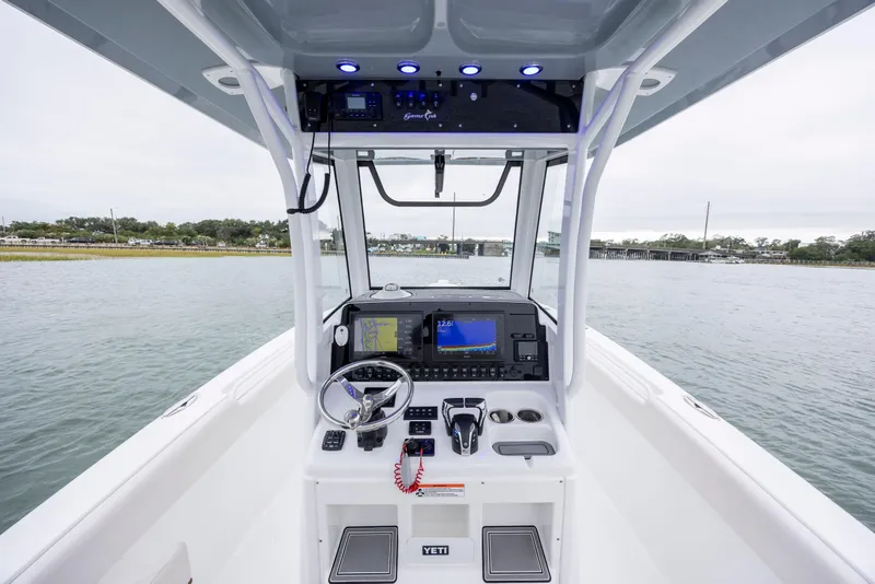 Slide: The Image of 2021 Sea Hunt Gamefish 25 boat console with navigation equipment on calm water. - 9