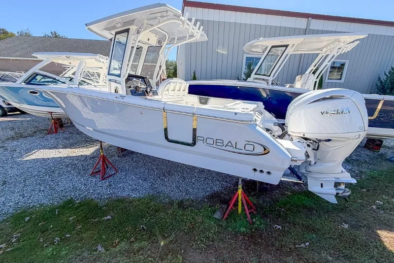 The Image of 2024 Robalo R250 Center Console boat displayed outdoors on stands. - 1