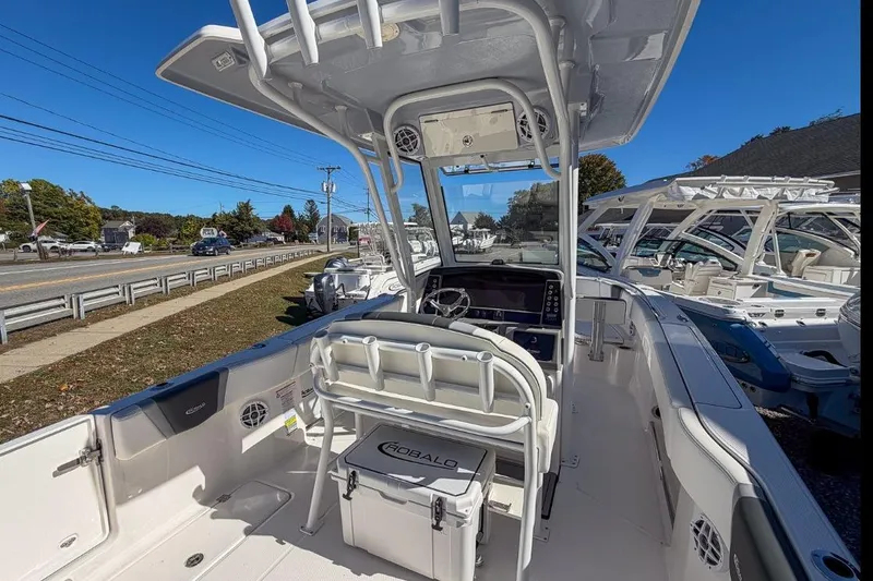 Slide: The Image of 2024 Robalo R250 Center Console boat interior with helm and seating, docked outdoors. - 12