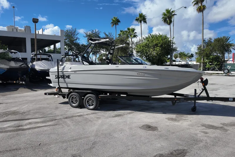 Slide: The Image of 2025 Supreme S220 boat on trailer, parked outdoors under a clear blue sky. - 3