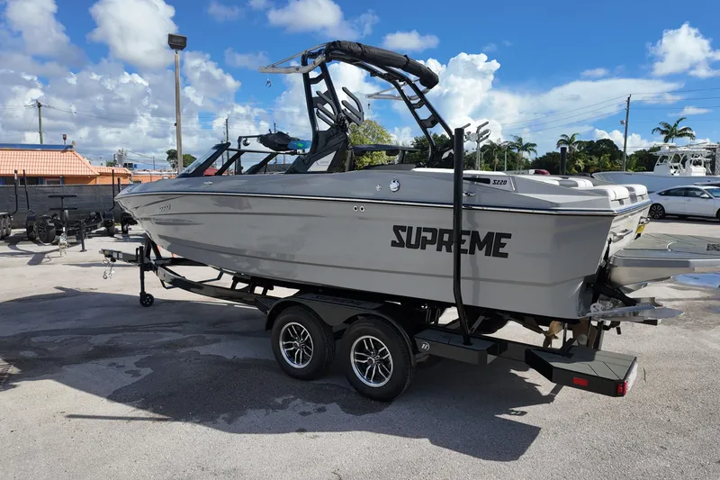 Slide: The Image of 2025 Supreme S220 boat on trailer under clear blue sky. - 8