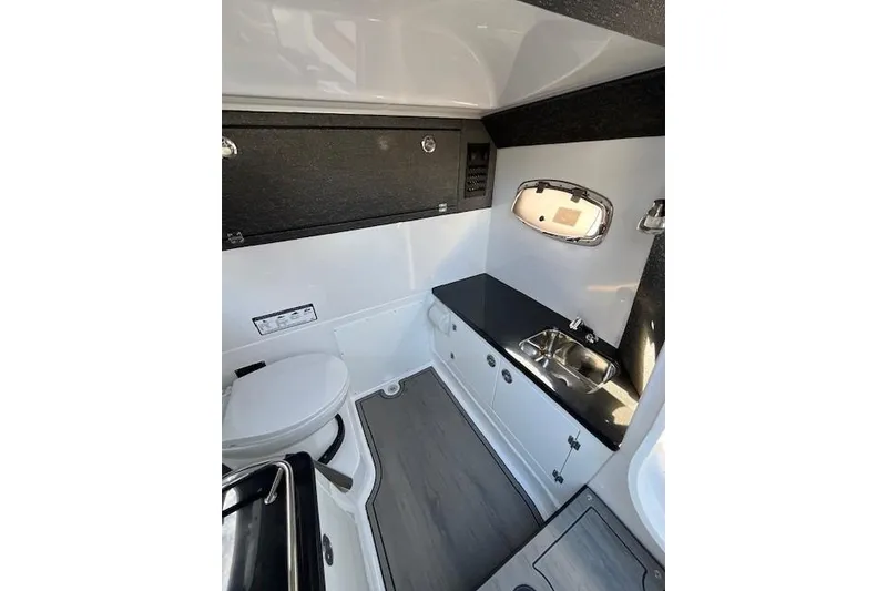Slide: The Image of Interior of 2026 Monterey Elite 27 SD boat featuring a compact bathroom with sink and toilet. - 14