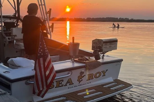 Slide: The Image of 1994 Albemarle Sportfish boat at sunset with American flag and paddleboarders in the background. - 5