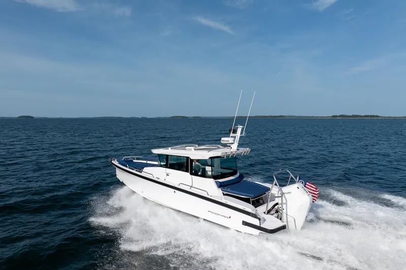 Slide: The Image of 2026 Axopar 29 Cross Cabin boat interior with person navigating on open water. - 4