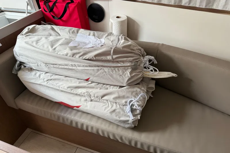 Slide: The Image of Beneteau Oceanis 35.1 interior with stacked sail bags on beige seating, 2021 model. - 15