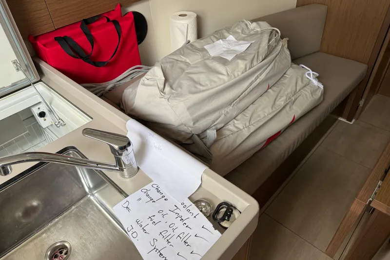 Slide: The Image of Interior of 2021 Beneteau Oceanis 35.1 with sink, red bag, and folded sail. - 19