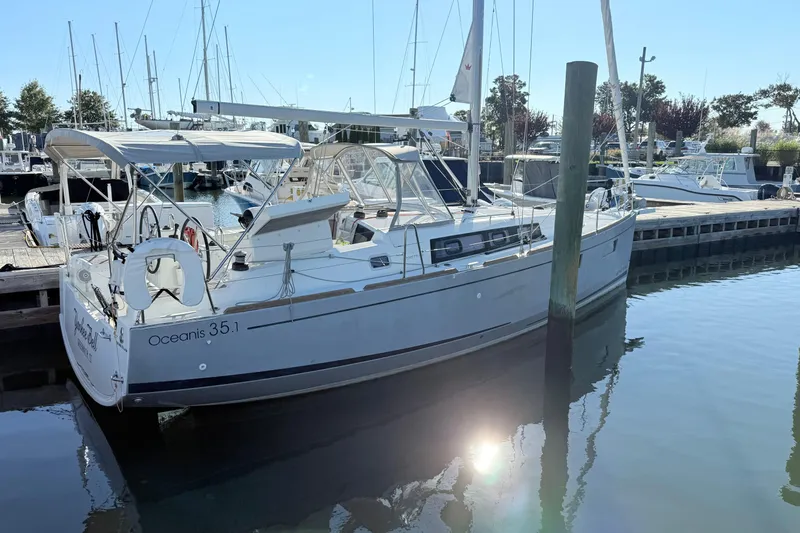 Slide: The Image of 2021 Beneteau Oceanis 35.1 sailboat docked at marina, reflecting on calm water. - 3